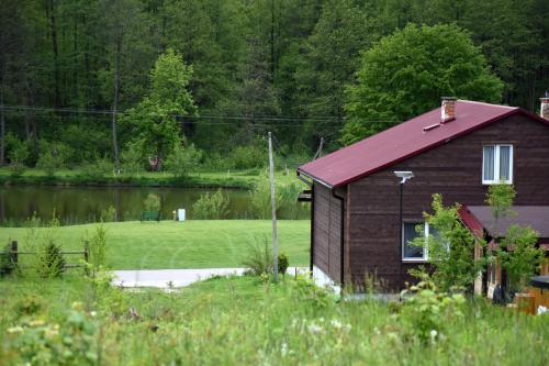 a house with a red roof next to a lake at Agroturystyka w Dolinie Raty in Prusie