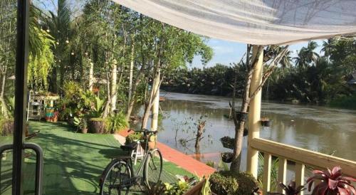 a bike parked on a porch next to a river at River Jam Amphawa in Amphawa