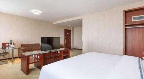 a hotel room with a bed and a flat screen tv at City Comfort Inn Xiangyang Railway Station in Xiangyang
