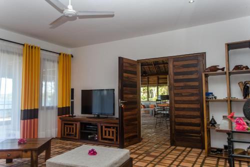a living room with a flat screen tv and an open door at Home The Residence in Befotaka Bay