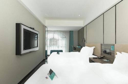 a hotel room with two beds and a flat screen tv at Xana Lite Xichang Hangtian Avenue Branch in Xichang