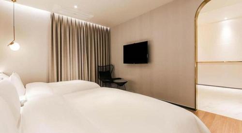 a hotel room with a white bed and a chair at Gimhae Perfect Hotel in Gimhae