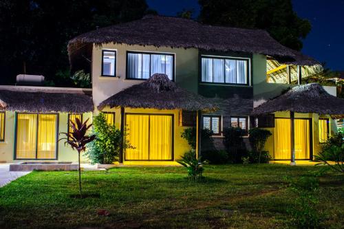 a house with yellow doors and a grass yard at Home The Residence in Befotaka Bay