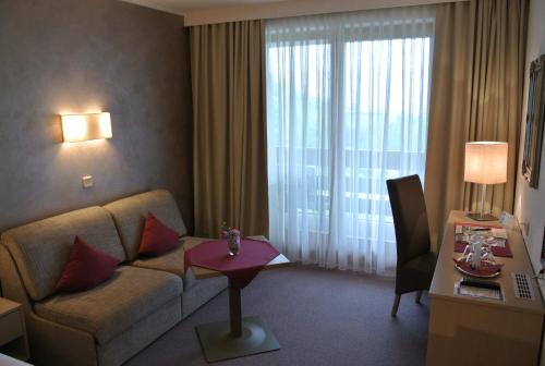 a living room with a couch and a table in a room at Dei Hotel Schönblick in Velden am Wörthersee