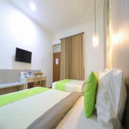 a hotel room with two beds with green pillows at Hotel Huswah Airport in Jakarta