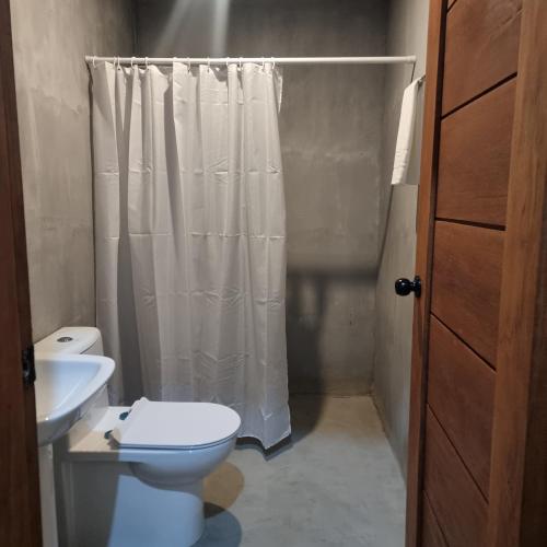ein Badezimmer mit Toilette und Duschvorhang in der Unterkunft Mulawin B&B in El Nido