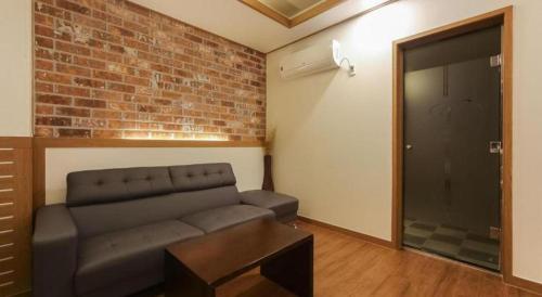 a living room with a couch and a brick wall at H Hotel in Ulsan