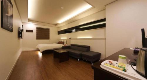 a living room with a couch and a bed at H Hotel in Ulsan