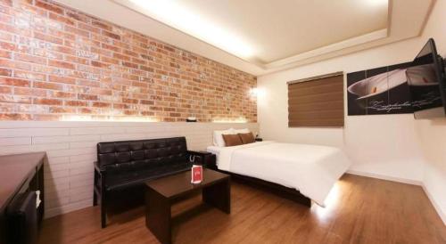 a room with a bed and a couch and a brick wall at H Hotel in Ulsan