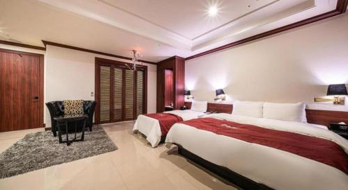a large hotel room with two beds and a chair at Hotel Floce in Bucheon
