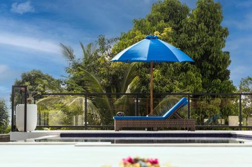 a blue umbrella sitting on a bench next to a pool at WiNy Kubu Reod in Sukasada