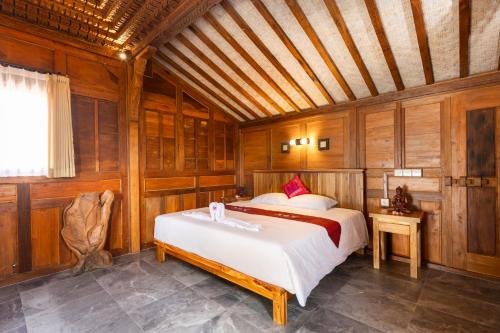 a bedroom with a bed and a wooden ceiling at WiNy Kubu Reod in Sukasada