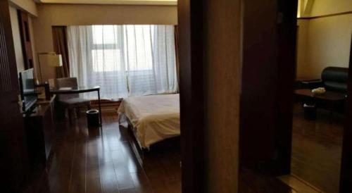 a bedroom with a bed and a desk and a window at Starmoon Hotel in Beijing