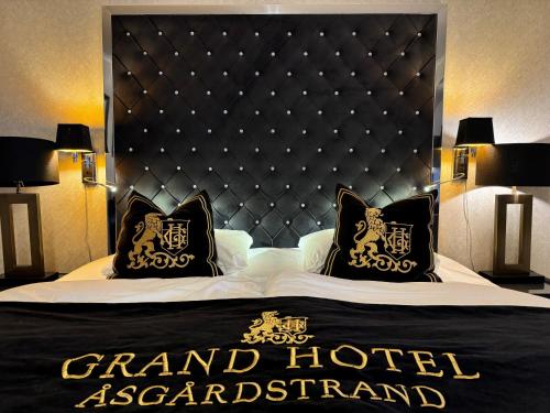 a large bed with a black headboard and two pillows at Grand Hotel Åsgårdstrand - Unike Hoteller in Åsgårdstrand