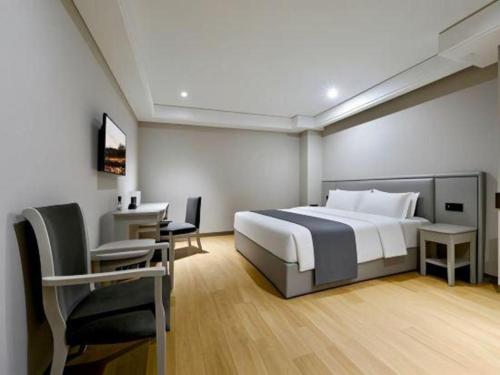 a hotel room with a bed and a desk and a chair at GreenTree Inn Fuyang Yijing International North Business in Fuyang