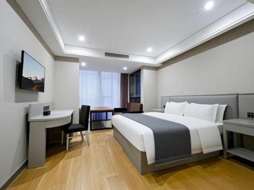 a hotel room with a large bed and a desk at GreenTree Inn Fuyang Yijing International North Business in Fuyang
