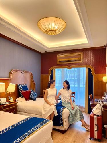 two women sitting on a bed in a hotel room at Riviera Hotel in Dubai