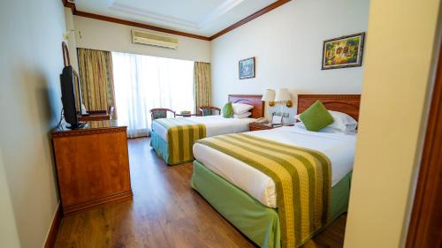 a hotel room with two beds and a television at Riviera Hotel in Dubai