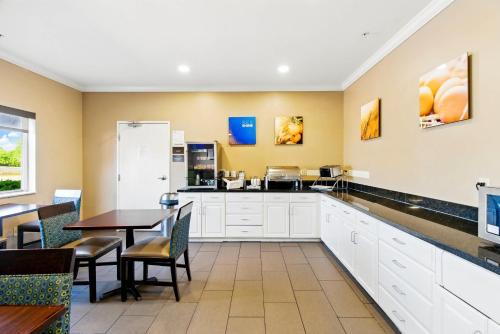 a kitchen with white cabinets and a table and chairs at Comfort Inn South Tulsa - Woodland Hills in Tulsa