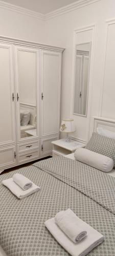 a white bedroom with two beds with towels on them at Bulevar Mostar Old Bridge in Mostar