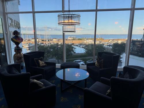 a room with chairs and a table and a chandelier at Grand Hotel Åsgårdstrand - Unike Hoteller in Åsgårdstrand
