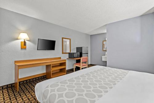 a hotel room with a bed and a desk with a computer at Rodeway Inn Albuquerque West in Albuquerque