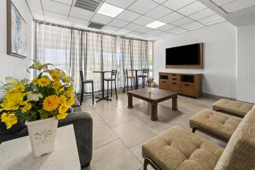 a living room with a couch and a table with yellow flowers at Suburban Studios Fairborn - Dayton in Fairborn