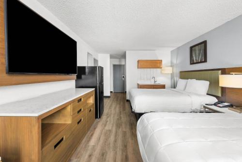 a hotel room with two beds and a flat screen tv at Suburban Studios Fairborn - Dayton in Fairborn