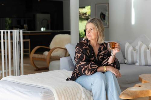una mujer sentada en un sofá sosteniendo una taza de café en Casa Scenic MacMasters Beach, en Macmasters Beach