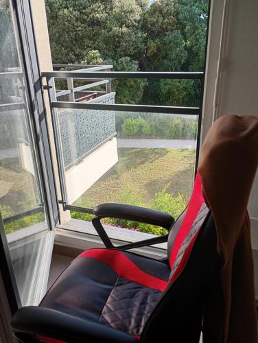 une chaise rouge assise devant une fenêtre dans l'établissement Chambre 1 personne, à La Celle-sous-Gouzon