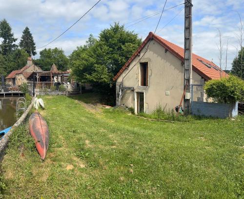 une maison et un bateau sur l'herbe à côté d'une maison dans l'établissement Maison Moulin Martin, à Chiddes