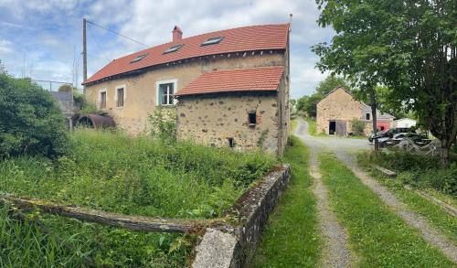 un bâtiment avec un toit rouge et un chemin de terre dans l'établissement Maison Moulin Martin, à Chiddes