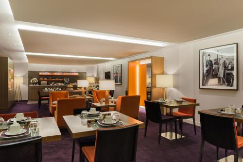 a restaurant with tables and chairs and a fireplace at Hôtel le Derby Alma by Inwood Hotels in Paris
