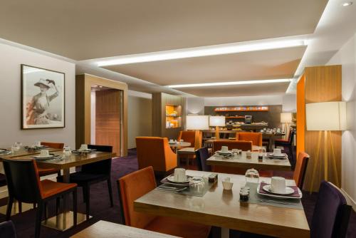 a restaurant with tables and chairs and a kitchen at Hôtel le Derby Alma by Inwood Hotels in Paris