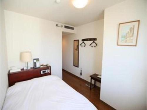 a white bedroom with a bed and a table at Fukuyama Terminal Hotel in Onomichi