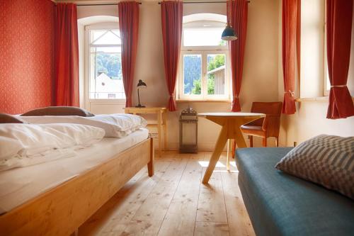 1 Schlafzimmer mit 2 Betten, einem Tisch und einem Fenster in der Unterkunft Bio-Hotel Zur Mühle in Bad Schandau