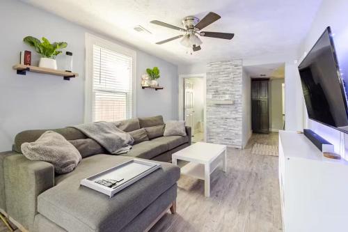 a living room with a couch and a flat screen tv at The Little Blue Haus - Two Miles to Broadway in Nashville