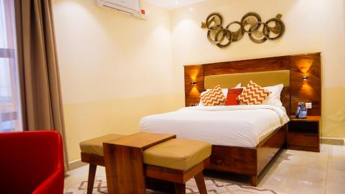 a hotel room with a bed and a red chair at Millennium Terrace Hotel in Kampala
