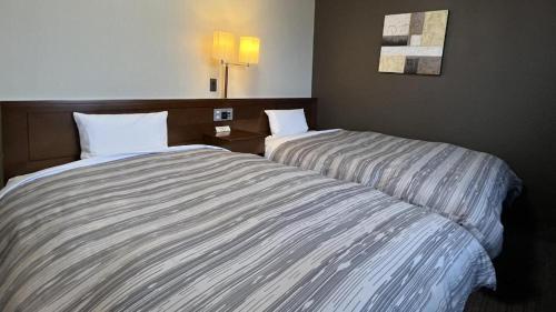 two beds sitting next to each other in a room at Hotel Route Inn Furukawa Ekimae in Osaki