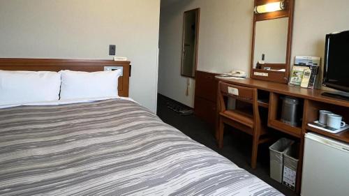 a hotel room with a bed and a desk at Hotel Route Inn Furukawa Ekimae in Osaki