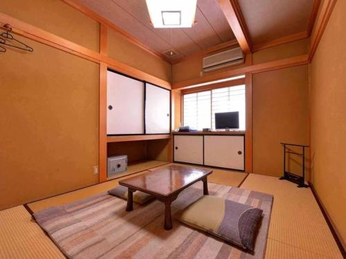 a living room with a coffee table and a window at Minshuku Shima in Kaga