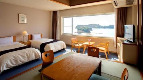 a hotel room with two beds and a table and a window at Shodoshima International Hotel in Fuchisaki