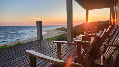 a deck with chairs and the beach at sunset at The View - Xai Xai Mozambique Xai Xai Beach Front 180 Degree Sea Views in Xai-Xai