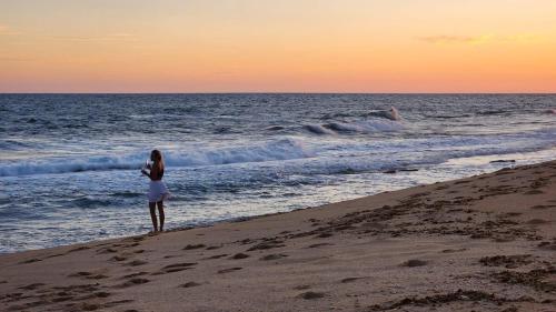 a woman standing on the beach looking at the ocean at The View - Xai Xai Mozambique Xai Xai Beach Front 180 Degree Sea Views in Xai-Xai