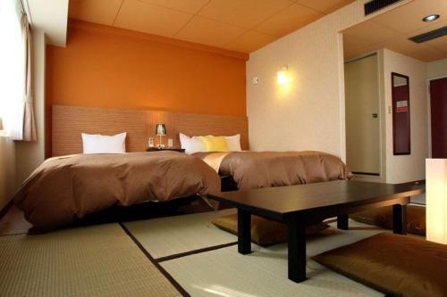 a hotel room with two beds and a table at Hotel 1-2-3 Kofu Shingen Onsen in Kofu