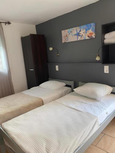 two twin beds in a room with a wall at Hotel Clair Logis in Argelès-sur-Mer