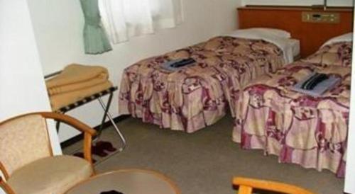 a hotel room with two beds and a table and chairs at Mimatsu Hotel in Mito