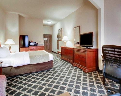 a hotel room with a bed and a flat screen tv at Clarion Suites Vidalia Riverfront in Vidalia