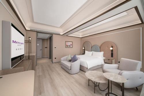 a hotel room with a bed and a flat screen tv at Mercure Guangzhou Financial City in Guangzhou