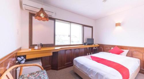 a bedroom with a bed and a desk and a window at Tabist Hotel Sankoen in Hitachi